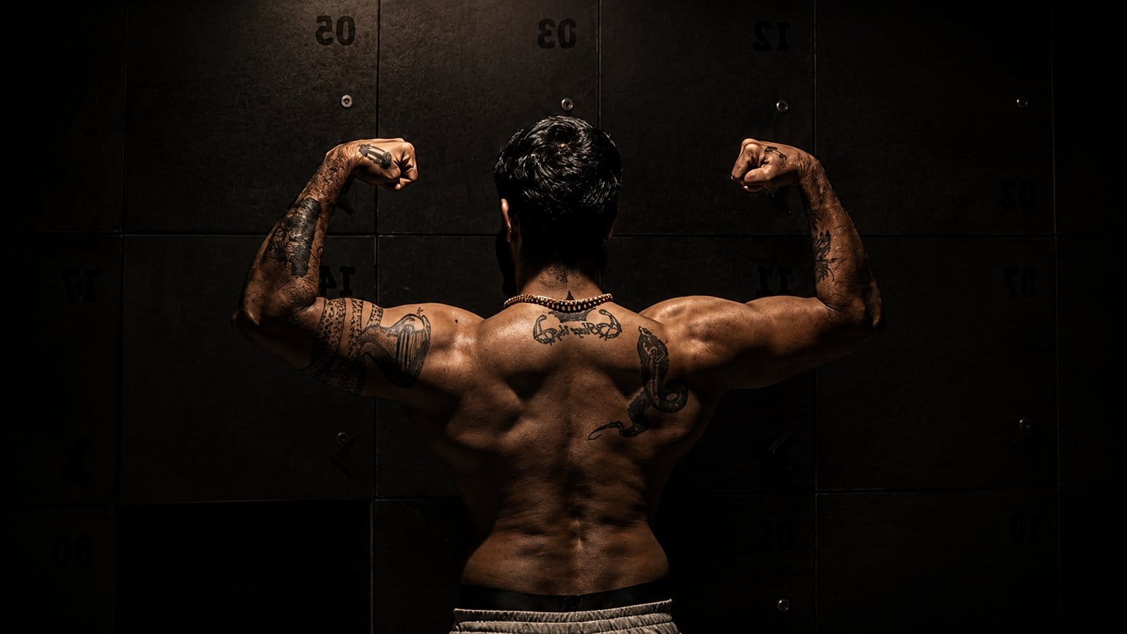 Athlete holding a strong back double-biceps pose in cinematic warm light